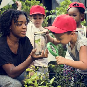 teacher showing young students plant in jar