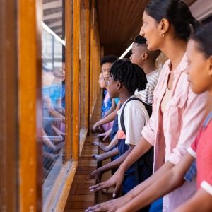 Students and teacher looking out window, observing outside school building.