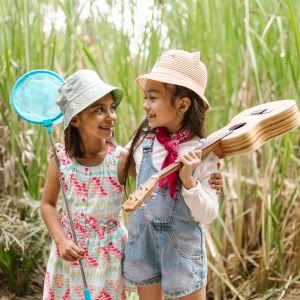 Two girls looking at each other in front of tall grass