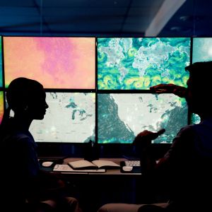 Computer, screen and maps with people in control room for storm tracking, satellite forecast or planning weather pattern. Back, meteorology team or radar data for climate monitor, silhouette or night