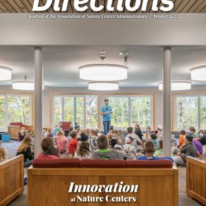 Cover of the journal: A group of children sits and looks at an adult in the middle of an open indoor space.   Text at top reads: "Directions — Journal of the Association of Nature Center Administrators // Winter 2022"  Text at bottom reads: "Innovation at Nature Centers / Director's Notes / Sustainable Construction / Pareidolia"