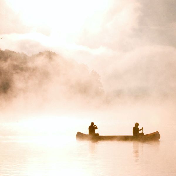 Two people in a canoe on a lake on a misty day