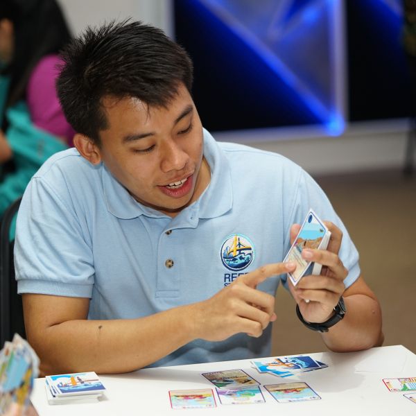 Reef Stakes co-founded showing a deck of Reef Stakes cards to some card players.