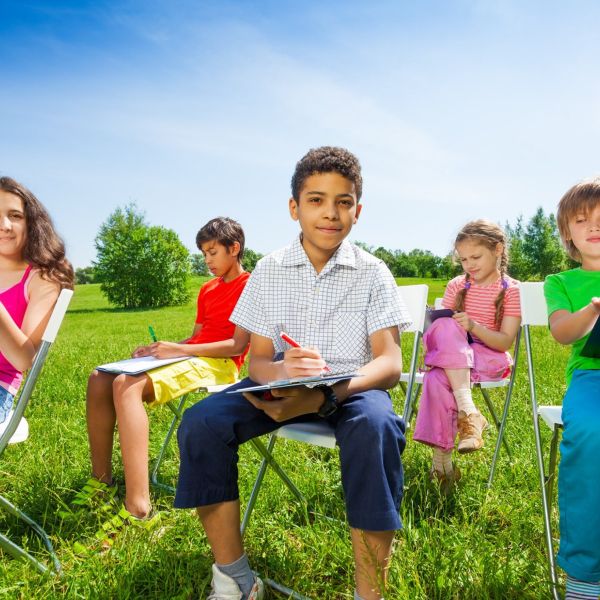 students with clipboards seated in chairs outdoors