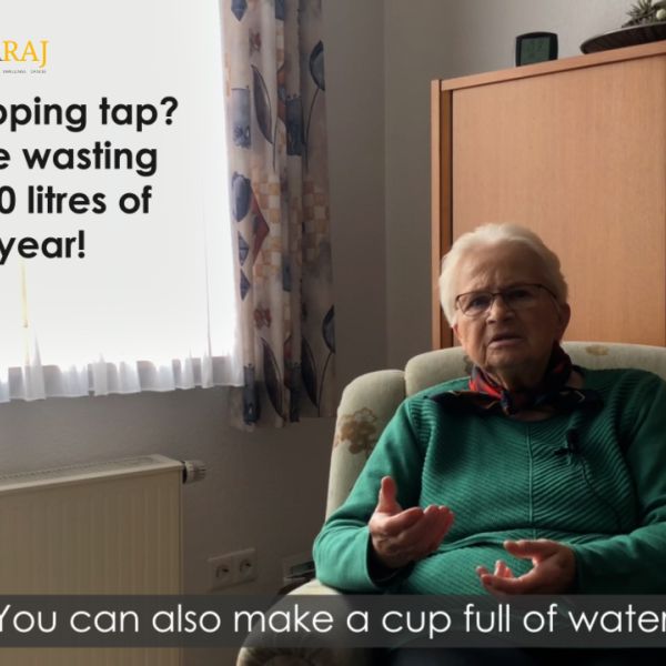 An elderly woman with short white hair, wearing a green sweater, sits in an armchair while talking to an off-camera interviewer. Text overlay shows logos for the H2Our Project and 5swaraj, with the text "Spotted a dripping tap? This could be wasting around 5,500 litres of water a year!"