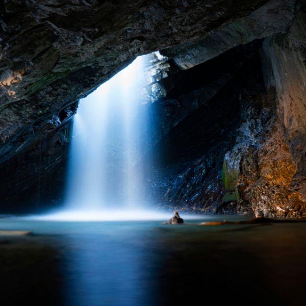 Waterfall dropping down from a hole inside of a cave on a cold autumn day in Big Cottonwood Canyon located in Utah.