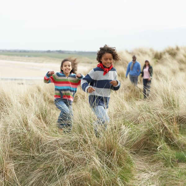 two young children running in grass ahead of two adults