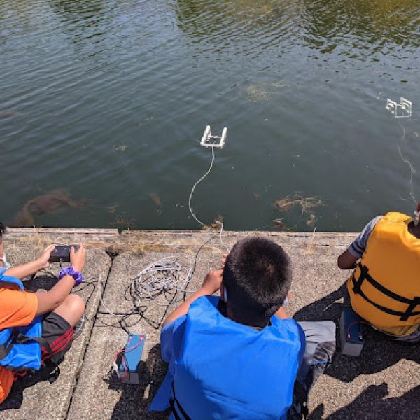 Three kids sitting on a dock.