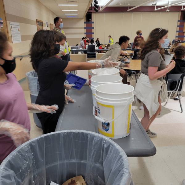 Students reach to collect leftover lunches from their peers at Prairie View Middle School