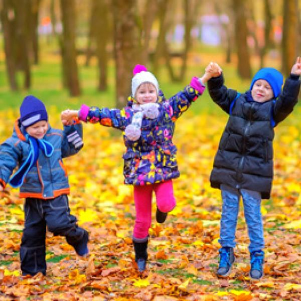 three young children in woods with yellow leaves on ground