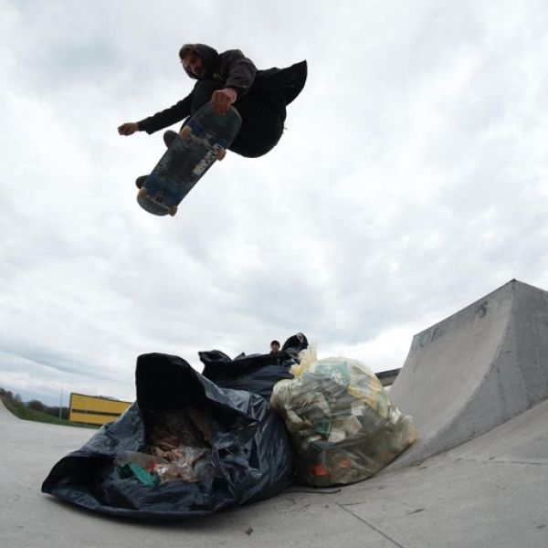 Skateboarder jumping a bag of trash. 