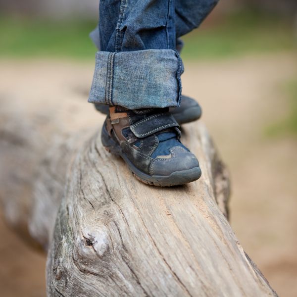 Photo of a child walking on a log, but photo only shows up to shoes.