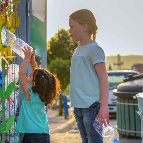 Two kids recycling plastic bottles