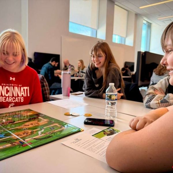 People sit at a table and play the ATi board game