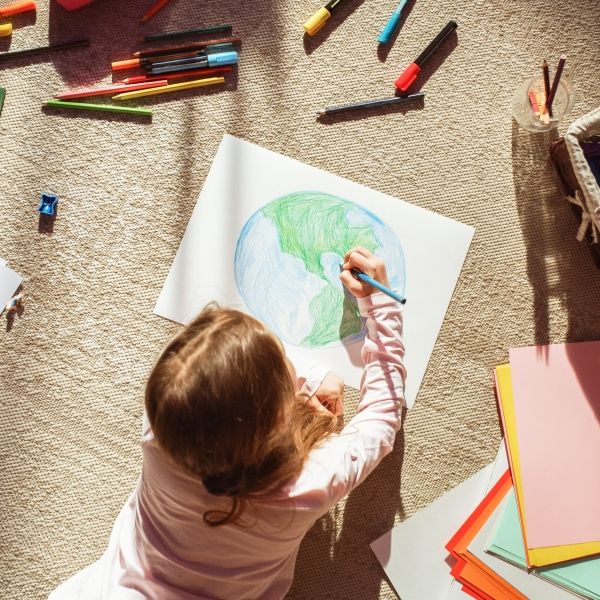 Child uses coloring pencils to draw Earth