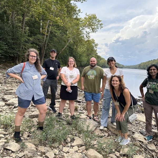 Group of environmental education practitioners taking a photo on the banks of a river. 