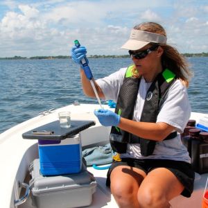 Person on a boat holding a test tube out at sea